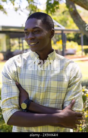 African American young man wearing yellow plaid shirt, standing outside Stock Photo
