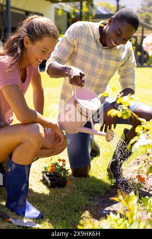 A diverse young couple watering plants outside Stock Photo