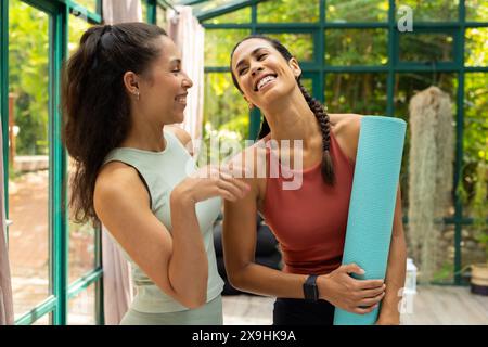 Glass house studio hosting diverse female yoga students Stock Photo