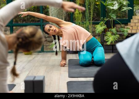 At glass house studio, diverse yoga students and instructor, guiding Stock Photo