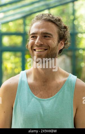 At Glass House Studio, Caucasian male in blue tank smiling during outdoor yoga Stock Photo