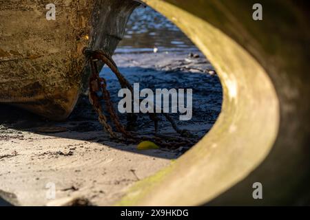 Ropes and chains of old dingy boat on the sandy shore line Stock Photo