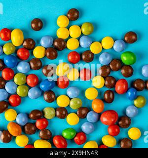 multicolored chocolate candies on colored background, top down studio photo Stock Photo