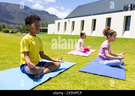 Biracial boy and girls practice yoga outdoors on mats Stock Photo