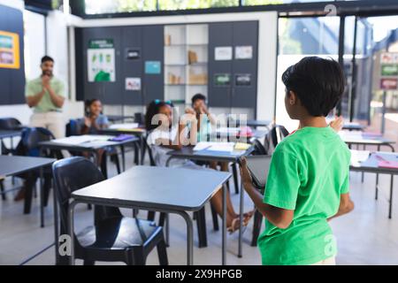 In school, young Asian male teacher watches as diverse students present with copy space Stock Photo