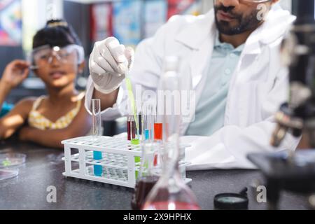 Young Asian male teacher conducting an experiment in school, biracial girl observing with interest Stock Photo