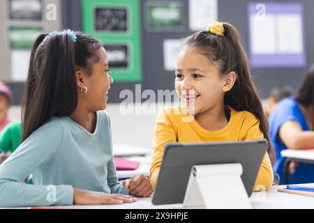 In school, biracial teacher guiding her diverse students during lesson in classroom Stock Photo