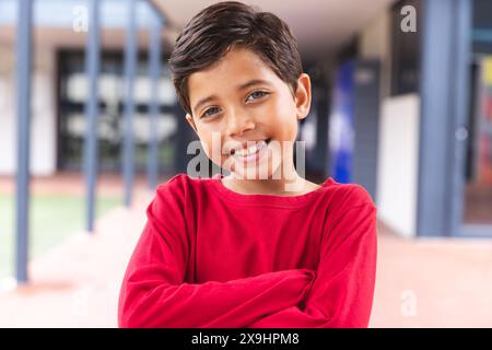 In school, outdoors, biracial young boy standing, smiling at camera Stock Photo