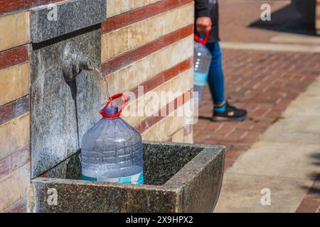 A large plastic bottle is being filled up with water from a hot spring in Central Sofia, Bulgaria Stock Photo