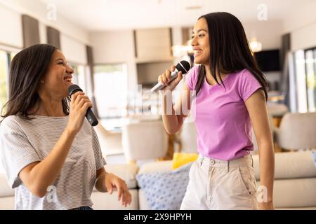 Biracial young sisters singing with microphones at home Stock Photo