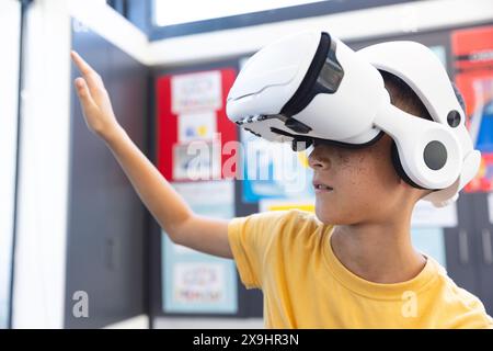 Biracial boy explores virtual reality in a school setting Stock Photo