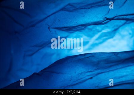 Extreme close up of blue empty plastic bag background. The plastic surface is wrinkly and tattered making abstract pattern. Selective focus, shallow d Stock Photo