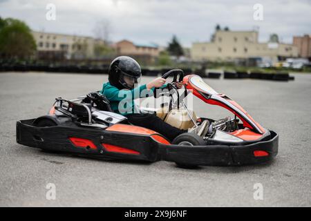Kid in a black helmet driving a go-kart during an intense race. Experience the thrill and excitement of go-kart racing. Stock Photo