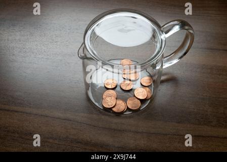 A glass container, money box, with some one cent, dollar cents, US currency, symbol for poverty Stock Photo