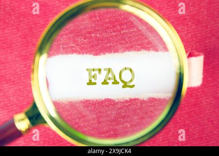 FAQ concept through a magnifying glass under a torn piece of red paper Stock Photo