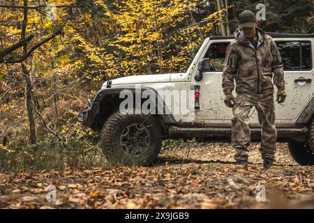 Man Standing By White Jeep In Autumn Forest Stock Photo