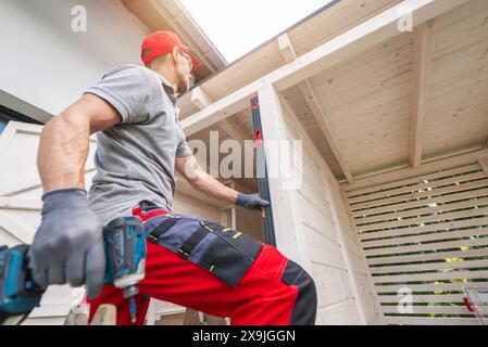 Caucasian Construction Worker Using Level on Wooden Structure Stock Photo