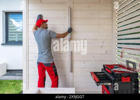 Contractor Using Level on Wooden Wall During Construction Stock Photo
