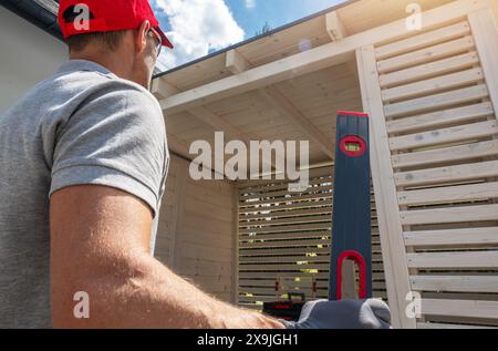Construction Worker Checking Level of Wooden Structure Stock Photo