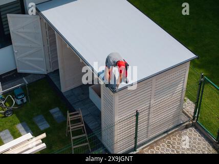 Worker Installing Roof on Wooden Shed Stock Photo