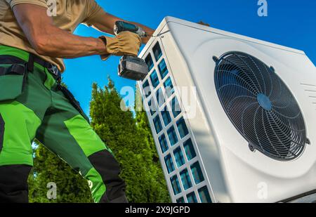 Technician Installing Hat Pump Unit Outdoors Stock Photo