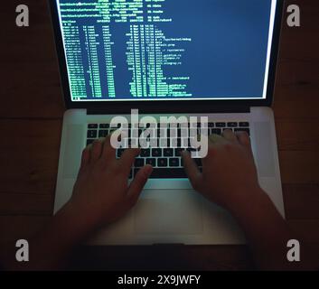 Coding, hands and hacker on laptop at night as malware thief for hacking database software, hardware virus or firewall error. Spy, typing or criminal Stock Photo