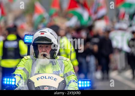 Police bike rider oversees the crowd at the Palestinian protest Manchester. A car crashed into a tram in St Peters square after traffic was stopped in the centre due to a Palestinian demonstration in Manchester city centre. The protest saw protesters pass down Market street passing a Barclays Bank branch which has been boarded up after windows were smashed and the building was covered in red paint as part of a protest againts the Banks involvement with investment in Israel. Manchester, UK  Picture: garyroberts/worldwidefeatures.com Stock Photo