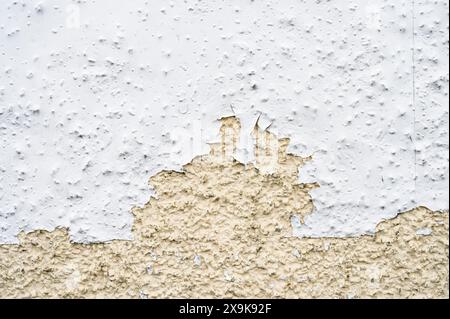 Damaged white paint peeling from a pebble dash wall Stock Photo