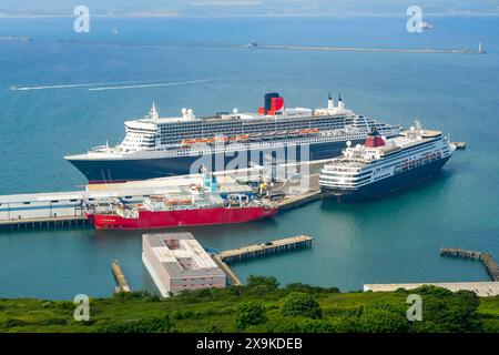 Portland Port, Dorset, UK.  1st June 2024.  UK Weather.  The Cunard cruise liner Queen Mary 2 docked at Portland Port in Dorset on a hot sunny day.  The famous liner is docked near to the Bibby Stockholm asylum immigration barge.  Picture Credit: Graham Hunt/Alamy Live News Stock Photo