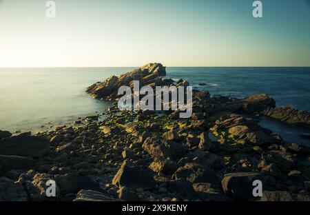 coastal landscape in which an old loading dock juts into the sea, long exposure photo with green and bluish tones Stock Photo