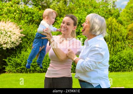 A heartwarming image of three generations sharing a joyful moment in a beautiful garden. Stock Photo