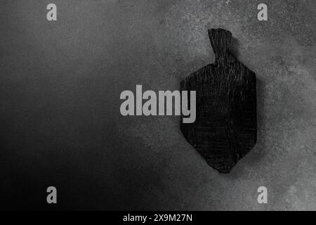 Black wooden cutting board elegantly presented against a dark backdrop. Ideal for culinary-themed designs, food blogs, or kitchen-related content, add Stock Photo