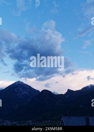 Dramatic grey and white clouds over silhouetted alpine mountains in the Aosta Valley, NW Italy. June 01, 2024 Stock Photo