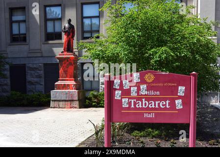 Ottawa, Canada - June 1, 2024: Statue of J.H. Tabaret at the University of Ottawa was covered in red paint on May 24. Tabaret was considered a founder of the University. Stickers calling out Jacques Fremont, President of the University, have been added to the Tabaret Hall sign. No one has claimed responsibility for the act. The grounds of Tabaret Hall are now covered with tents as Pro-Palestinian protesters demand that University disclose and divest any Investments it has with companies and organizations with ties to Israel. Stock Photo