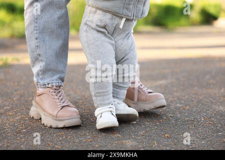 Mother teaching her baby how to walk outdoors, closeup Stock Photo