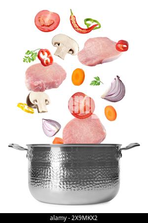 Fresh ingredients falling into saucepan on white background Stock Photo