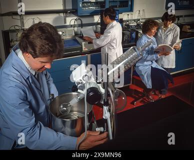 Scientists and students working in laboratory with glassware and equipment, conducting experiments and reviewing data in modern research setting Stock Photo