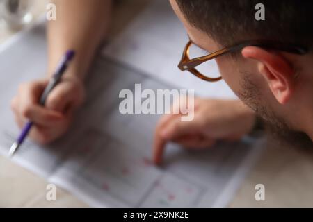 Team of architects planning, close-up of architectural drawing, office workspace. Architectural design process with brainstorming session. Architect Stock Photo