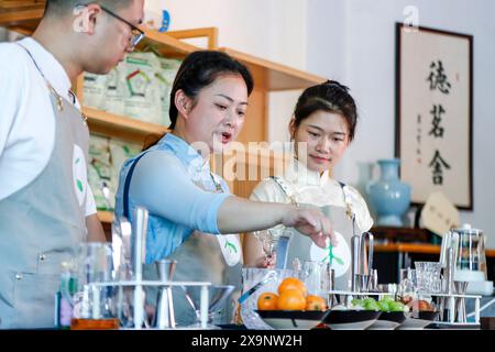 (240602) -- HUANGSHAN, June 2, 2024 (Xinhua) -- Wang Sun (C) gives instructions to her apprentices at Demingshe, a tea art vocational training school in Huangshan City, east China's Anhui Province, May 23, 2024. Wang Sun is the founder of Demingshe, a tea art vocational training school in Huangshan City. Huangshan City is the place of origin of several famous teas including Huangshan Maofeng, Taiping Houkui and Keemun black tea, and boasts a long history of drinking tea. As a pioneer in developing innovative tea-making skills and alternative ways of drinking tea, Wang started the researc Stock Photo