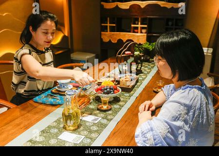 (240602) -- HUANGSHAN, June 2, 2024 (Xinhua) -- Customers drink tea beverages at a shop in Huangshan City, east China's Anhui Province, May 23, 2024. Wang Sun is the founder of Demingshe, a tea art vocational training school in Huangshan City. Huangshan City is the place of origin of several famous teas including Huangshan Maofeng, Taiping Houkui and Keemun black tea, and boasts a long history of drinking tea. As a pioneer in developing innovative tea-making skills and alternative ways of drinking tea, Wang started the research and promotion of the new-style tea beverages in 2021. Inspir Stock Photo