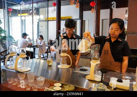 (240602) -- HUANGSHAN, June 2, 2024 (Xinhua) -- Tea mixologists make beverages at a shop in Huangshan City, east China's Anhui Province, May 23, 2024. Wang Sun is the founder of Demingshe, a tea art vocational training school in Huangshan City. Huangshan City is the place of origin of several famous teas including Huangshan Maofeng, Taiping Houkui and Keemun black tea, and boasts a long history of drinking tea. As a pioneer in developing innovative tea-making skills and alternative ways of drinking tea, Wang started the research and promotion of the new-style tea beverages in 2021. Inspi Stock Photo