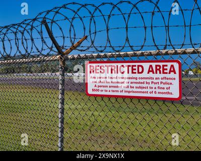 St Lucia - Jan 30 2024: A prominent sign fixed to a fence topped with razor wire states that the area beyond is restricted and that anyone found tresp Stock Photo