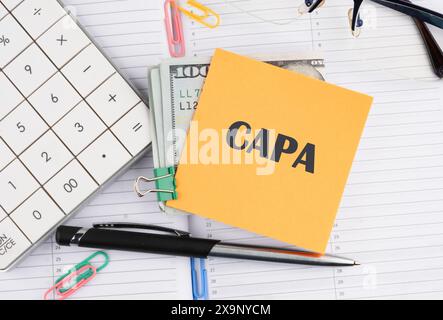 Words CAPA Corrective and Preventive action plans written on a yellow sticker with money on a business notebook Stock Photo