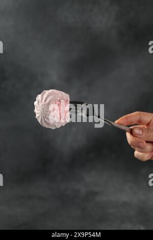 pink marshmallows on a fork on a black background Stock Photo