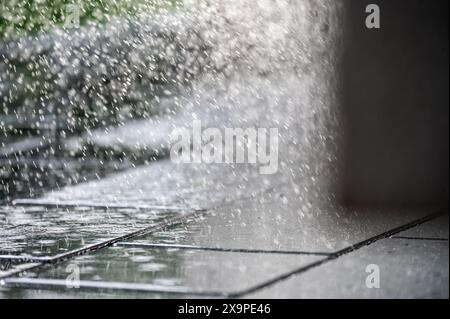 Captivating scene of water splashing dynamically on glossy, wet tiles illuminated by daylight, creating a vivid urban atmosphere. Stock Photo