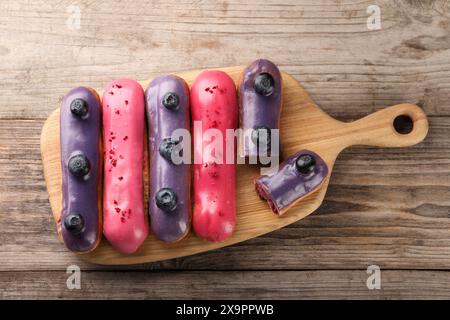 Different tasty glazed eclairs on wooden table, top view Stock Photo