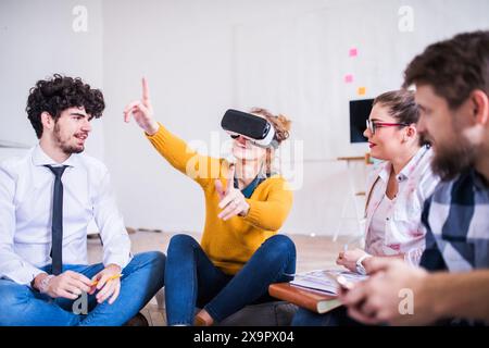 Young group of colleagues using VR technology in startup company office. Virtual reality in business. Stock Photo