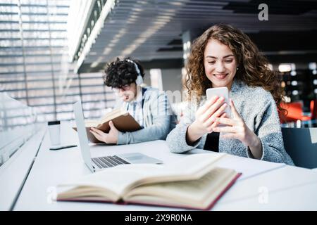 Young female student in library, focusing on final project, presentation. University student preparing for final exam. Stock Photo