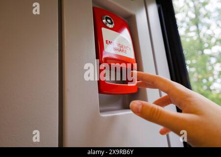 In the image, a person is activating a red button mounted on a wall. The scene depicts a gesture involving a finger pressing the button, with elements Stock Photo