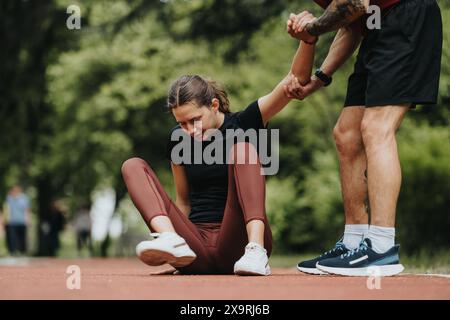 Fit man assists injured woman with leg pain during outdoor run Stock Photo